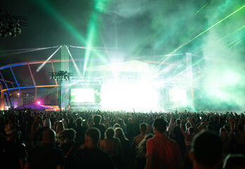 Neon stage lights flashing at a concert. Audience partying and dancing