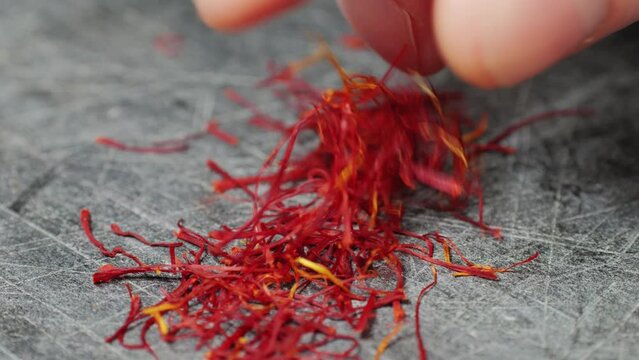 Dried crimson saffron on grey desk close-up macro. Orange red spice for food. Crocus sativus flower saffron