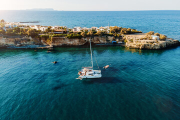 Drone view of Catamaran anchored in blue sea with swimming people. Travel background. Cruise vacation.