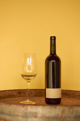 A bottle of wine and a glass placed on top of a barrel