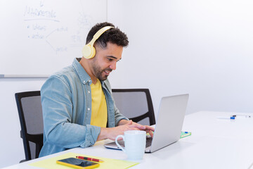 Businessman with headphones while working on a laptop in the office. Business and technology concept.