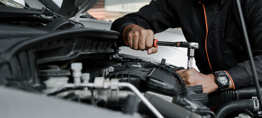 Mechanic fixing a car at home. Repair and service. - obrazy, fototapety, plakaty