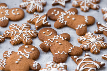 Obraz na płótnie Canvas Homemade gingerbread Christmas cookies in icing sugar. Delicious gingerbread cookies on the background of a bokeh of Christmas tree lights. Freshly baked Christmas gingerbread cookies.