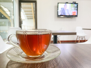 A cup of hot tea with puffs of smoke in a transparent glass on a table in a waiting room. Concept for relaxation, breakfast and working breaktime