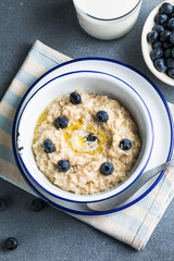 Oatmeal porridge in white bowl, close up view.Oatmeal bowl. Oat porridge with banana, blueberry, walnut, chia seeds and oat milk for healthy breakfast. Healthy diet food. Top view