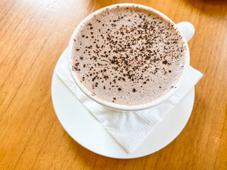 Hot Milk Chocolate Drink in white porcelain mug on a wooden table. Concept for breakfast, working, task, job, business plan. Empty blank copy text space.