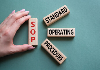 SOP - Standard Operating Procedure symbol. Wooden blocks with word SLA. Businessman hand. Beautiful grey green background. Business and Service Level Agreement concept. Copy space.