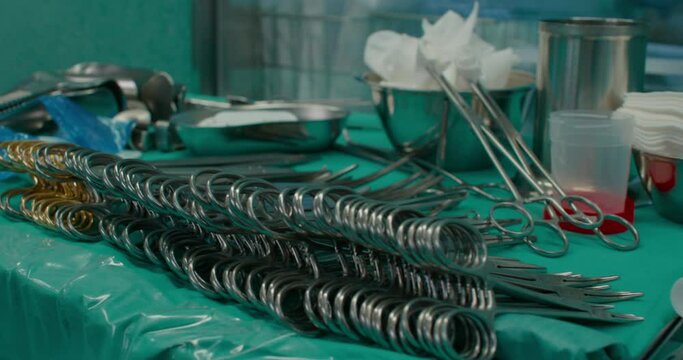 Close up shot of different sterilized surgical instruments laid out on table in operating room, ready for surgery. allis, babcock, dunhills and other forceps and retractors