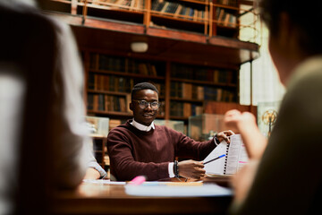 Young male student having discussion in library study hall