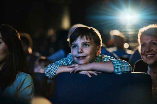 Cute little boy enjoying movie in cinema theater