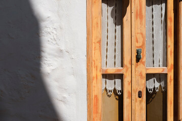 old wooden greek aegean or mediterranean window yeallow painted  with handmade white curtains
