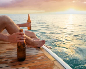 Fototapeten Party with friends. Close up male hand holding bottle of beer on the yacht sailing the sea. © luengo_ua