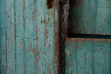 very old turquoise door, rustic paint, broken entrance, rusty metal chain and lock