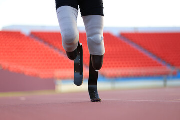 disabled man with a leg prosthesis in sports clothing is running in the stadium