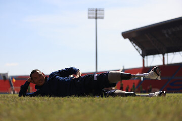 sportsman warming up before running practice on a grass field  stadium  stretching muscles on track,