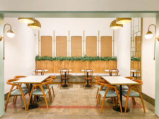 Cafe tables and chairs set made of solid wood against a bright wooden wall background with ivy...
