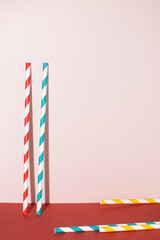 Multicolored drinking straws on pink and red background. Event and party concept with copy space.
