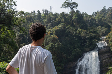 Guy staring at a waterfall in a natural environment in the south of India