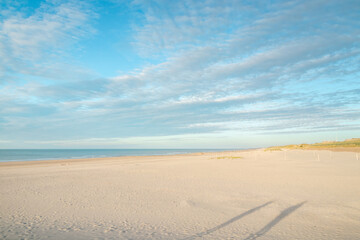Silhouette of a man waving at the world from a pier on a beach near Oostende, Belgium. Sandy beaches by the Atlantic Ocean