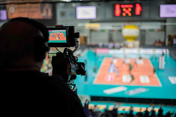 Professional TV camera in sports hall during volleyball match.