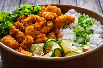 Korean fried chicken - seared breaded chicken nuggets served with white rice and vegetables on wooden table
