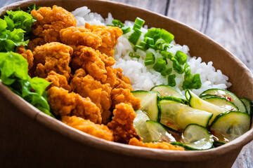 Korean fried chicken - seared breaded chicken nuggets served with white rice and vegetables on wooden table
