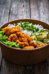 Korean fried chicken - seared breaded chicken nuggets served with white rice and vegetables on wooden table
