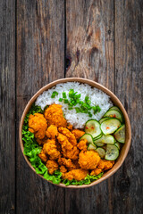 Korean fried chicken - seared breaded chicken nuggets served with white rice and vegetables on wooden table
