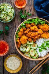 Korean fried chicken - seared breaded chicken nuggets served with white rice and vegetables on wooden table
