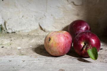 Composition of three ripe red apples lie on a white floor