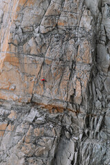 Rock climber suspended on top rope on large rock face