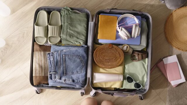 Packing suitcase top view, going on trip, don't forget condoms. Prioritizing safe sex, woman ensures protection by packing condoms for vacation. Health care and preventing unwanted consequences.
