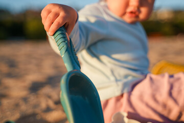Little baby child toddler plays in the sand with a paddle on the beach