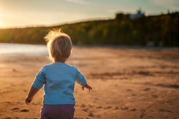 Little baby child toddler walks along an empty beach by the sea at sunset alone, calm and relax,...