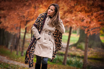young girl in coat in forest. Fashion woman in coat in park. Slim young fashion model wearing white coat outdoor. Beautiful woman in leopard coat  in the autumn park
