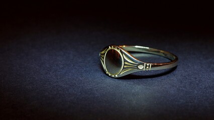 Women's gold signet ring on a black background.