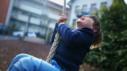 Obraz premium Child Holding Tight and Sliding to End of Wire Rope at Public Park, Young Boy Having Fun in Nostalgic Childhood Moment, Close-Up Slide on Park Wire