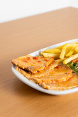 Traditional Portuguese dish: Oven-roasted pork loin with crispy potatoes & mixed salad served in a cozy snack bar.