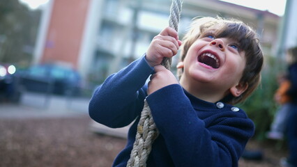 Obraz premium Child Holding Tight and Sliding to End of Wire Rope at Public Park, Young Boy Having Fun in Nostalgic Childhood Moment, Close-Up Slide on Park Wire