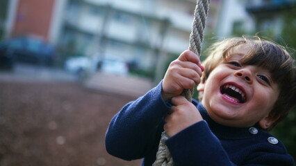 Obraz premium Child Holding Tight and Sliding to End of Wire Rope at Public Park, Young Boy Having Fun in Nostalgic Childhood Moment, Close-Up Slide on Park Wire