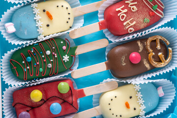 Christmas dessert. Sweet food. Cheesecake on a stick in the shape of ice cream. Children's treat in winter. Candy Christmas tree, snowman, deer and Santa Claus. Gingerbread cookies.