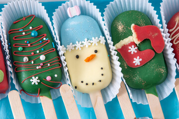 Christmas dessert. Sweet food. Cheesecake on a stick in the shape of ice cream. Children's treat in winter. Candy Christmas tree, snowman, deer and Santa Claus. Gingerbread cookies.