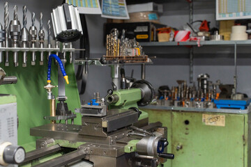  A lathe machine in a workshop with various tools and bits in the background, indicating a space...