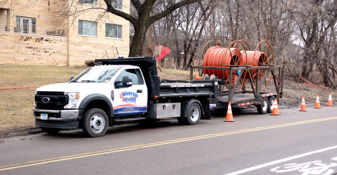 A Universal Services truck carrying large rolls of orange conduit to carry buried electronic cable. St Paul Minnesota MN USA