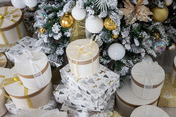 luxury decorated golden gift boxes under Christmas tree, New Year home decorations, golden wrapping of Santa presents, festive tree decorated with garland, baubles, traditional celebration.