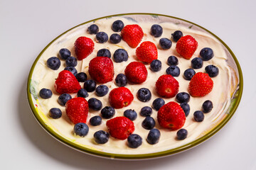 Fresh juicy strawberries and blueberries blueberries in heavy whipped cream in a plate