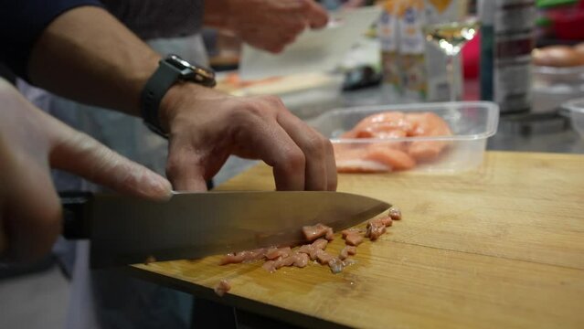 Mincing fresh salmon in the kitchen with sharp knife for cooking fish tartare dish