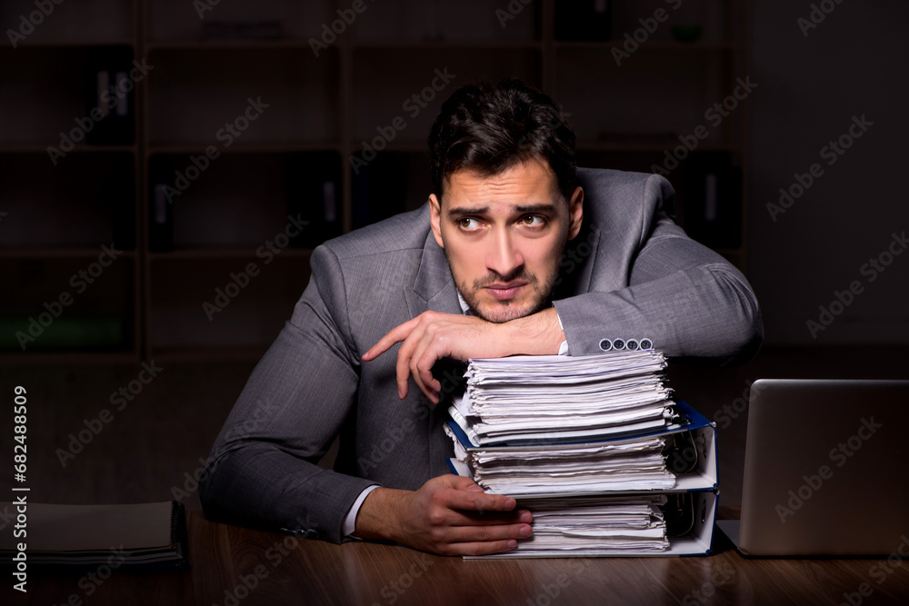 Wall mural Young male employee working late in the office