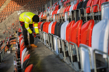 A worker screws in a screw while replacing seats at the stadium