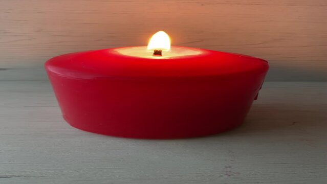 burning red candle on a light wooden background and vertical

